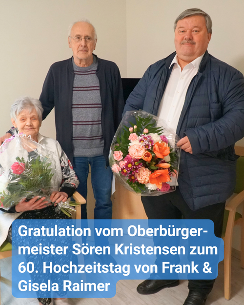 Ein älteres Ehepaar bekommt Blumensträuße zum Jubiläum geschenkt. Bildbeschriftung: Gratulation vom Oberbürgermeister Sören Kristensen zum 60. Hochzeitstag von Frank & Gisela Raimer